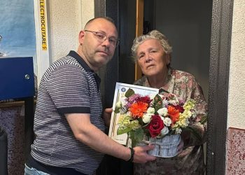 Șeful Inspectoratului Școlar Suceava, Ciprian Anton, cu un coș cu flori și cu o diplomă, la fosta lui învățătoare, Leontina Ciobanu, de Ziua Învățătorului