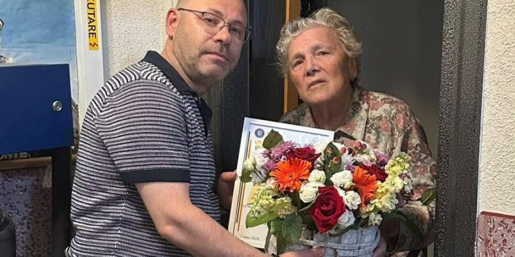 Șeful Inspectoratului Școlar Suceava, Ciprian Anton, cu un coș cu flori și cu o diplomă, la fosta lui învățătoare, Leontina Ciobanu, de Ziua Învățătorului